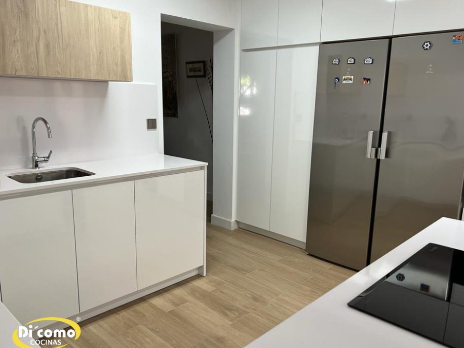 Cocina moderna en blanco brillo con columnas hasta el techo y frigorífico americano de acero