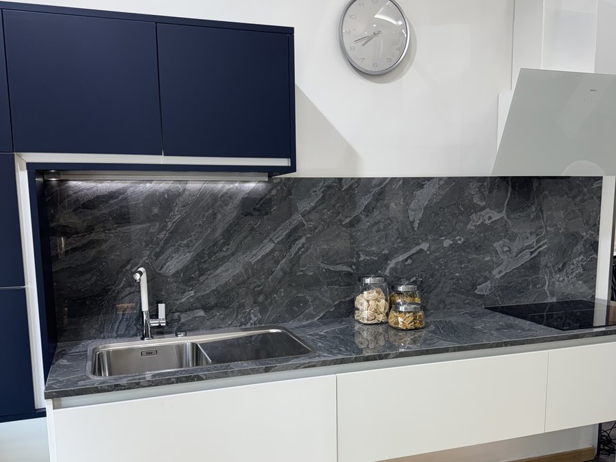 Fregadero integrado en encimera de piedra natural oscura, combinada con mueble azul marino